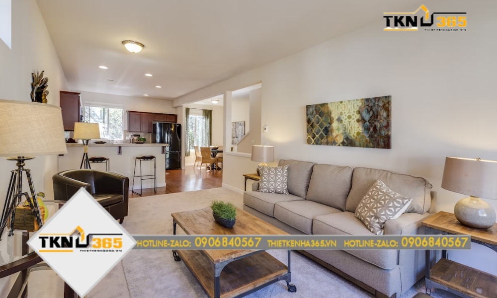 Một căn phòng khách với tone màu xám sáng, kết hợp với đồ nội thất gỗ trang trí, nối liền với nhà bếp và khu vực ăn uống, tạo không gian ấm cúng và thoải mái