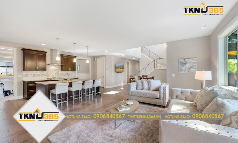 Một căn phòng khách với tone màu trầm ấm tích hợp cùng nhà bếp và nhà ăn dùng đồ nội thất gỗ, tạo không gian sang trọng và trang nhã